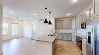Located on Hill Branch Road in Flat Rock, NC, this well-designed three-bedroom, two-bathroom single-story home offers a thoughtfully efficient layout with quality finishes throughout. The kitchen serves as the heart of the home, showcasing sage-toned shaker cabinets, a classic white subway tile backsplash, granite countertops, and a center island with an undermount sink illuminated by two statement black pendant lights. Stainless steel appliances, including a refrigerator, range, and microwave, complete the space. Light wood-look flooring flows through the main living and kitchen areas, contributing to a bright and cohesive aesthetic. The living area features recessed lighting, a ceiling fan, and a door with adjacent window that invites natural light. The primary bedroom is generously sized and connects to a well-appointed en-suite bathroom featuring a double-sink granite vanity with sage cabinetry, a glass-enclosed shower with subway tile, and a spacious walk-in closet with wire shelving. The second bathroom mirrors the home's consistent design with granite counters, a tub-shower combo with subway tile, and matching cabinetry. Secondary bedrooms are carpeted and include closets with built-in shelving, offering practical storage solutions throughout.