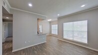 Located at 3787 Perrin Central Blvd in San Antonio, Texas, this single-story residence offers a clean, modern interior with a thoughtfully designed layout. The open living and dining area features wood-look plank flooring, neutral gray walls, crown molding, and recessed lighting, creating a bright and welcoming atmosphere. Large windows fitted with blinds allow abundant natural light to fill the space throughout the day.

The kitchen is equipped with dark cabinetry, granite-look countertops, a stainless steel sink with a flexible faucet, and stainless steel appliances including a refrigerator, microwave, and range. A pass-through counter connects the kitchen to the living area, enhancing the open-concept feel.

The bedrooms are carpeted for comfort and include ceiling fan fixtures and windows that bring in natural light. Closet storage is also available within the bedroom areas.

The bathrooms feature a tub-shower combination with white tile surround, granite-top vanities, and dark cabinetry — one bathroom showcasing a bold blue vanity as a standout design element. Wood-look flooring completes the bathroom spaces.

The entry area offers a welcoming foyer with plank flooring and recessed lighting, setting the tone for the well-maintained interior found throughout this San Antonio residence.