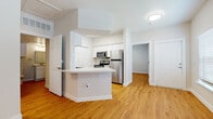 This single-floor residential unit offers a bright, cohesive interior defined by warm hardwood-style flooring that flows seamlessly throughout every room. The kitchen serves as a functional centerpiece, featuring white shaker cabinetry, light quartz-style countertops, stainless steel appliances including a refrigerator, microwave, and range, and a peninsula that provides additional prep and casual dining space. A pantry closet adds generous storage to the kitchen area.

The bedrooms are comfortably sized, each benefiting from ceiling fans, neutral wall tones, and windows fitted with blinds that allow for controlled natural light. One bedroom features a walk-in closet, while the layout connects rooms with easy accessibility. An entry area with a six-panel door welcomes residents into the open living space.

Two bathrooms mirror each other in design, each outfitted with white vanity cabinetry, light countertops, framed mirrors, a tub-shower combination, and ample overhead lighting. White upper cabinets provide extra storage in each bath. The consistent use of white finishes and warm flooring throughout gives the entire unit a clean, updated aesthetic that feels open and move-in ready.