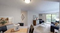 Located at 84 Hawthorne Dr N in New London, CT, this two-bedroom, one-bathroom unit offers a well-organized single-floor layout designed for comfortable everyday living. The living room is bright and welcoming, featuring carpeted floors, a wall-mounted air conditioning unit, and a sliding glass door that opens onto a private balcony overlooking a canopy of mature trees and lush greenery — providing a tranquil, nature-filled backdrop. The living area flows into a dedicated dining space, making the layout practical for both relaxing and entertaining. The kitchen is equipped with warm oak cabinetry, a tile backsplash, a double-basin sink, and white appliances including a range and refrigerator. Both bedrooms are carpeted and feature windows that bring in natural light and views of the surrounding foliage. The primary bedroom offers ample room for a bed and workspace, while the second bedroom provides a clean, versatile space. The bathroom is finished in a bright, neutral palette with a full tub-shower combination, a single vanity with mirror, and wood-look flooring. The covered balcony, accessible from the living room, completes the unit with an inviting outdoor retreat surrounded by greenery.