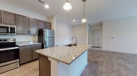 Located at 2024 Barr Rd in Kannapolis, NC, this single-floor residence offers a well-designed layout with modern finishes throughout. The kitchen is a standout feature, showcasing rich dark cabinetry, granite countertops, and a full suite of stainless steel appliances including a refrigerator, electric range, and over-the-range microwave. A central island with a granite surface and undermount sink serves as both a functional workspace and a gathering point, illuminated by stylish pendant lighting. The open-concept layout connects the kitchen to a spacious living area finished with durable wood-look flooring and neutral walls that allow for natural light to flow freely through large windows. The bedrooms are carpeted for comfort and include ceiling fans, ample closet space, and access to adjoining bathrooms. One bathroom features a walk-in glass-door shower with built-in shelving, while a second bathroom is equipped with a full tub-shower combination and a granite-topped vanity with dark cabinetry. Throughout the residence, recessed lighting, clean white trim, and a consistent neutral color palette contribute to a bright, cohesive, and move-in-ready atmosphere.