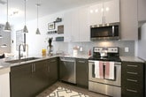 This single-floor residence at 2204 Duluth Highway 120 in Duluth, GA presents a thoughtfully designed open-concept layout with contemporary finishes throughout. The kitchen is a standout feature, equipped with stainless steel appliances including a French door refrigerator, electric range, microwave, and dishwasher. Two-tone cabinetry pairs dark lower cabinets with crisp white uppers, complemented by granite countertops and a tile backsplash. A peninsula with bar seating connects the kitchen to the living area, where wood-look plank flooring extends throughout the main space, adding warmth and cohesion.

The bedroom offers a serene retreat with neutral-toned walls, plush carpeting, and a large window with outdoor views that allows ample natural light. The space is further enhanced by access to a generously sized walk-in closet featuring extensive wire shelving and hanging rods for organized storage. The bathroom is finished with wood-look flooring, a dark vanity with granite countertop, and a full tub-shower combination. Clean white walls and consistent design choices throughout create a cohesive, modern ambiance suited for comfortable everyday living.