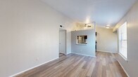 This single-story residence offers a functional and well-appointed layout with consistent wood-look flooring running throughout every room. The open living area is a standout feature, boasting vaulted ceilings and a ceiling fan that enhance the sense of airiness and volume. A half-wall partition with a pass-through window connects the living space to the kitchen, maintaining an open feel while defining each zone. The kitchen is equipped with stainless steel appliances, including a gas range and refrigerator, complemented by dark cabinetry, a tile backsplash, a speckled countertop, and built-in open shelving for additional storage. The bedroom is generously proportioned, featuring a window that allows natural light to filter in, and includes access to a dedicated walk-in closet — offering ample storage space. A second room off the main hallway provides additional flexible space. The full bathroom is cleanly finished with a tub-shower combination, white tile surround, a dark wood vanity, and a speckled countertop. Throughout the residence, neutral wall tones and clean white trim create a cohesive, move-in-ready aesthetic that is both practical and inviting.