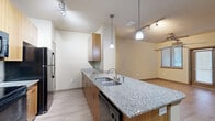 Located at 4652 Miramar Dr in St. Petersburg, FL, this one-bedroom, two-bathroom residence offers a well-planned single-floor layout that makes efficient use of its space. The open-concept kitchen serves as the heart of the home, featuring light wood cabinetry, granite countertops, a breakfast bar peninsula with pendant lighting, track lighting overhead, and black appliances including a refrigerator and range. The kitchen flows seamlessly into the living area, which is finished with light hardwood-style flooring and a ceiling fan, creating a bright and airy atmosphere. The generously sized primary bedroom is carpeted for comfort and includes a ceiling fan, a window with blinds for natural light, and direct access to both a full bathroom and a dedicated walk-in closet. The walk-in closet is outfitted with wire shelving across multiple walls, offering ample storage. Both bathrooms are well-appointed, with one featuring tile flooring, a wood-toned vanity with a stone countertop, a large mirror, and a full soaking tub with tiled surround. Neutral tones and clean finishes throughout give the space a cohesive and inviting feel.