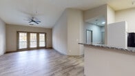 Located at 400 England Pointe Dr in Fredericksburg, VA, this well-appointed single-floor unit offers a thoughtfully designed open-concept layout bathed in natural light. The spacious living room is a standout feature, boasting soaring vaulted ceilings, a ceiling fan, and floor-to-ceiling French doors that open to the outdoors, creating an airy, welcoming atmosphere. Light wood-style flooring flows seamlessly throughout the entire unit, adding warmth and visual continuity.

The kitchen is both functional and stylish, featuring granite countertops with a contrasting two-tone cabinetry design — white upper cabinets paired with gray lower cabinets — along with stainless steel appliances including a range, microwave, and a skylight that brightens the space. A peninsula counter connects the kitchen to the open dining area, which is accented by a pendant light fixture.

Multiple bedrooms offer generous proportions, each equipped with ceiling fans and large windows that frame outdoor greenery, providing ample natural light and ventilation. The bathroom includes a full tub-shower combination with white tile surround and wood-style flooring. A dedicated in-unit laundry room houses a full-size washer and dryer with overhead shelving, adding everyday convenience to this clean, modern home.