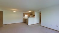 Located at 5222 Flower Valley Dr in Canal Winchester, Ohio, this single-floor residence offers a functional and comfortable layout designed for everyday living. The open-concept floor plan seamlessly connects the living area to the kitchen, creating a spacious and accessible environment throughout.

The living area is finished with wall-to-wall carpeting in a neutral tone, providing a warm and inviting atmosphere. A pendant light fixture adds a subtle decorative touch overhead, complementing the ambient ceiling lighting throughout the space.

The kitchen is positioned along one wall and features warm-toned wood cabinetry that provides ample storage. A peninsula-style counter with a half-wall divider separates the kitchen from the living area while maintaining an open sightline between the two spaces. Standard appliances, including a range and refrigerator, are included. A bright floral arrangement on the counter adds a welcoming touch.

A hallway visible from the main living area leads to additional rooms, suggesting a practical and well-organized floor plan. The textured ceiling and clean white walls throughout contribute to a bright, neutral interior that offers a versatile backdrop for a variety of furnishing styles. Overall, the space presents a straightforward, well-maintained single-floor layout suited for comfortable residential living.
