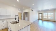 Located at 102 E Farwell in Spokane, WA, this thoughtfully designed 2-bedroom, 2-bathroom unit offers a clean, modern aesthetic throughout. The open-concept kitchen and living area serves as the heart of the unit, featuring light wood-style flooring, recessed lighting, and a seamless flow from room to room. The kitchen is well-appointed with white shaker cabinetry, quartz countertops, a large island with a deep single-basin sink and matte black faucet, and a full suite of stainless steel appliances including a refrigerator, range, and microwave. A convenient in-unit washer is tucked into a dedicated nook just off the main living area. The living room is bright and airy, with a wall-mounted mini-split system for climate control and a glass door opening to a private balcony. The spacious primary bedroom includes its own mini-split unit and walk-in closet with wire shelving. A second bedroom provides additional flexibility. Both bathrooms are finished with light gray vanities, gold hardware accents, quartz countertops, and wood-tone flooring. Each bathroom features a walk-in shower. Two generously sized closets offer ample storage throughout the unit, completing this modern and functional living space.