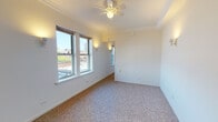 Located on N Kenmore Ave in Chicago's Edgewater neighborhood, this single-floor unit offers a functional and straightforward layout. The living area is finished with neutral-toned carpet and features crown molding along the ceiling, a ceiling fan with integrated lighting, and wall sconces that provide warm ambient illumination. Multiple windows allow natural light to fill the space while offering views of the surrounding Chicago cityscape, including neighboring rooftops and distant skyline elements.

The layout flows into a separate sleeping area, which mirrors the living space with carpeted flooring, crown molding, a ceiling fan, and generous windows capturing additional city views. An open closet with built-in shelving and a hanging rod provides practical storage. A secondary room near the entry offers access to a walk-in closet area and serves as a transitional space within the unit.

The galley-style kitchen is compact and efficient, featuring white cabinetry, open shelving, a gas range, a single-basin sink, tile backsplash, and a window overlooking the neighborhood. Vinyl tile flooring completes the kitchen area.

The bathroom retains classic Chicago character with white hexagonal penny tile flooring, subway tile walls, a wall-mounted vanity with cabinet storage, open shelving, a mirrored medicine cabinet, and a shower-tub combination. The overall aesthetic is clean, bright, and functional throughout.