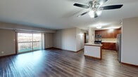 Located at 907 Vale Park Rd in Valparaiso, Indiana, this well-appointed single-floor unit offers an open-concept layout that seamlessly connects the living area and kitchen, creating a spacious and airy feel throughout. Rich hardwood-style flooring runs consistently across the entire space, complemented by neutral-toned walls and warm wood baseboards that add a refined touch.

The living area is generously sized and bathed in natural light from large sliding glass doors that open onto a private balcony, offering pleasant outdoor views. A ceiling fan with integrated lighting serves as both a functional and stylistic centerpiece overhead.

The kitchen is a standout feature, showcasing rich espresso-toned shaker-style cabinetry that extends to the ceiling for ample storage. Granite countertops, a classic subway tile backsplash, and a full suite of stainless steel appliances — including a gas range, microwave, dishwasher, and refrigerator — complete the space. A peninsula with an extended countertop provides additional workspace and casual seating.

The bedrooms are comfortably sized, each featuring the same hardwood-style flooring and windows that invite natural light. The overall ambiance of the unit is clean, modern, and move-in ready, making it a practical and attractive living space.