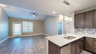 Located at 6131 Summit St in Shawnee, Kansas, this single-story residence offers a well-designed open-concept layout that seamlessly connects the kitchen, dining, and living areas. The living room is highlighted by vaulted ceilings that enhance the sense of spaciousness, wood-look plank flooring, a ceiling fan, and a door providing access to the exterior along with multiple windows that invite natural light.

The kitchen is a standout feature, equipped with rich dark-stained cabinetry, a decorative tile backsplash, stainless steel appliances including a refrigerator, range, and microwave, and a generous granite-topped island with an undermount double sink and pendant lighting overhead. Ample upper and lower cabinet storage adds practical functionality.

Bedroom spaces feature neutral-toned carpet, ceiling fans, and windows fitted with blinds. One bathroom includes a walk-in closet and a walk-in shower with built-in shelving and a curved curtain rod, finished with wood-look flooring that ties the space together cohesively.

Throughout, the unit maintains a consistent neutral color palette with warm beige and gray tones, white trim, and recessed lighting, contributing to a clean, modern aesthetic suited to everyday living.