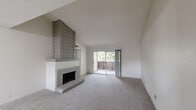 Located in Austin, TX, this single-floor residence offers a thoughtful layout across two bedrooms and two bathrooms. The living room serves as the centerpiece of the home, highlighted by a striking brick fireplace with a bold tile surround and vaulted ceilings that amplify the sense of space. Soft carpeting runs throughout the living area and bedrooms, adding warmth underfoot. A sliding glass door opens directly to a private balcony, framing lush outdoor views and allowing natural light to flood the interior.

The kitchen connects to the living and dining area via a pass-through counter with granite-style countertops, creating an open, communicative feel. The kitchen is equipped with standard appliances, white cabinetry, and a window above the sink for added brightness.

Both bedrooms are carpeted and feature windows dressed with blinds, providing natural light and privacy. The primary bedroom is generously sized and includes a walk-in closet with built-in shelving and hanging rods. Each bathroom is finished with wood-look vinyl flooring, a tub-shower combination, and a vanity with granite-style countertops. A connecting hallway and two closets complete the functional layout of this well-appointed Austin residence.