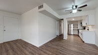 This well-appointed single-floor residence offers a clean, modern aesthetic defined by consistent wood-look plank flooring that runs throughout the main living areas and bedrooms, tying the space together cohesively. The open living and dining area is airy and welcoming, featuring a ceiling fan, a structural column accent, and a convenient entry point with a window that invites natural light. A soffit detail adds architectural interest to the transition between the living space and the kitchen.

The kitchen is a standout feature, outfitted with crisp white shaker-style cabinetry, matte black hardware, light quartz countertops, and a matte black gooseneck faucet at the undermount sink. Stainless steel appliances, including a full-size refrigerator and a gas range, complete the functional and stylish setup. Open shelving adds a contemporary touch.

The bedrooms are generously sized, bright, and versatile, each benefiting from natural light through window blinds and ceiling fans for year-round comfort. The bathrooms are well-maintained, featuring full tub-shower combinations — one with classic white subway tile surround and another with neutral beige tile — both finished with modern matte black fixtures, providing a cohesive design language throughout the home.
