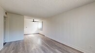 Located at 13200 Bromont Ave in Los Angeles, CA, this 1-bedroom, 1-bathroom unit offers a thoughtfully laid-out single-floor design. The open living area is bright and inviting, featuring light gray hardwood-style flooring, neutral white walls, a textured ceiling, and a ceiling fan. Large windows allow natural light to fill the space while offering pleasant outdoor views of surrounding greenery. The combined kitchen and living room layout maximizes functionality, with the kitchen showcasing warm honey-toned wood cabinetry, gray countertops, stainless steel appliances including an electric range and refrigerator, and a double stainless steel sink. The bedroom is a comfortable, carpeted retreat equipped with a ceiling fan, a spacious built-in closet with panel doors, and a window with garden views, adding a serene touch. The bathroom is clean and functional, featuring a tub/shower combo with chrome fixtures and wood-style flooring that ties back to the main living areas. Throughout the unit, the consistent use of neutral tones and modern finishes creates a cohesive, move-in-ready atmosphere ideal for comfortable everyday living.