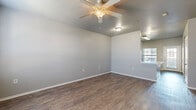 This single-story residence offers a practical and comfortable layout across two bedrooms, two bathrooms, a kitchen, living room, hallway, and four closets. The living area features warm wood-style vinyl flooring, neutral gray walls, and a ceiling fan with light fixture, creating a clean and inviting atmosphere. Natural light filters in through blinds-covered windows, adding brightness to the open feel of the space. The kitchen is well-equipped with white cabinetry, black appliances including a range, dishwasher, and refrigerator, complemented by a contrasting dark countertop and a dedicated pantry with built-in shelving. Wood-style flooring continues throughout the main living areas, maintaining a cohesive aesthetic. The primary bedroom is generously sized, featuring plush carpeting, a ceiling fan, a large window, and access to a closet with built-in shelving. The second bedroom also offers carpeted flooring, a ceiling fan, a bright window, and its own closet. Both bathrooms are finished with wood-style flooring and include a tub/shower combination with clean white surround and white cabinetry. The overall design is neutral and move-in ready, offering a functional and comfortable living environment.