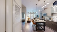Located at 611 S Street in Baltimore, MD, this single-floor residence offers a thoughtfully designed open-concept layout that seamlessly connects the kitchen, dining, and living areas. The kitchen is a standout feature, boasting sleek two-tone cabinetry with rich dark wood lower panels and light upper cabinets, granite countertops, a classic white subway tile backsplash, and a full suite of stainless steel appliances including a range, microwave, dishwasher, and French door refrigerator. A central kitchen island with seating provides an ideal spot for casual dining and entertaining. Durable wood-style flooring flows throughout the main living areas, complementing the contemporary aesthetic. The living area is bathed in natural light from large windows with floor-to-ceiling curtains, creating a warm and inviting ambiance. The bedroom is a serene retreat, highlighted by a striking textured accent wall in cool grey tones, large windows, and generous natural light. A spacious walk-in closet with wire shelving offers ample storage. The full bathroom features a soaking tub and shower combo, a dark wood vanity with a white countertop, and modern chrome fixtures, completing this well-appointed urban residence.