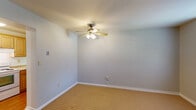 This single-floor space presents a straightforward and functional layout designed for comfortable everyday living. The living and bedroom areas are finished with warm-toned, textured carpeting that runs throughout, complemented by soft gray walls and clean white baseboards that lend a neutral, move-in-ready aesthetic. Several rooms feature ceiling fans with integrated lighting, providing both air circulation and overhead illumination. Natural light filters in through windows fitted with blinds, brightening the interior and enhancing the open feel of the carpeted rooms.

The kitchen is equipped with honey-toned wood cabinetry offering ample storage, light-colored countertops, a stainless steel sink, and a white electric range with an over-the-range ventilation hood. The layout is efficient and well-organized, making practical use of the available space.

The bathroom is finished with classic white square wall tiles that extend from floor to ceiling around the tub surround, paired with a standard soaking tub and shower combination fitted with chrome fixtures. A toilet and basic flooring complete the clean, utilitarian design.

Overall, the space maintains a consistent, understated palette throughout, with each area thoughtfully arranged to maximize function. The neutral tones and simple finishes provide a versatile canvas well-suited for a variety of uses and personal styles.
