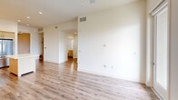 Located at 4201 Jamboree Rd in Newport Beach, California, this thoughtfully designed one-bedroom, one-bathroom residence offers a clean, modern aesthetic throughout its efficiently utilized single-floor layout. The open-concept living and kitchen area serves as the heart of the home, featuring light wood-look flooring, a ceiling fan, and large windows that invite abundant natural light while framing views of the surrounding Newport Beach cityscape. The contemporary kitchen is well-appointed with sleek white high-gloss cabinetry, warm wood-tone lower cabinets, a white quartz countertop with an undermount sink, a gas range, stainless steel appliances including a French door refrigerator, built-in microwave, and dishwasher — all underlining its functional elegance. The bedroom is carpeted for comfort and includes a ceiling fan, a dedicated closet with built-in shelving, and a large window offering elevated views of the city and surrounding greenery. The bathroom is finished with wood-look flooring, a marble-style tiled tub and shower surround, a clean white vanity with warm wood cabinetry, and recessed lighting. The overall palette of crisp whites and natural wood tones gives the space a bright, cohesive, and contemporary feel throughout.