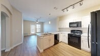 This thoughtfully designed 1-bedroom, 1-bathroom residence offers a functional and comfortable single-floor layout. The open-concept kitchen and living area serves as the heart of the home, featuring wood-style flooring that runs throughout the main living spaces. The kitchen is equipped with white shaker cabinetry, light stone-look countertops, a peninsula island with a double sink, black appliances including a refrigerator, electric range, microwave, and dishwasher, as well as track lighting and a pendant light for focused illumination. The living area extends naturally from the kitchen and benefits from a ceiling fan, an exterior door, and windows that invite natural light and outdoor views. An elegant arched doorway connects the living space to the hallway, adding an architectural detail that enhances the overall design. The spacious bedroom features soft carpeting, a ceiling fan, and a large window that fills the room with natural light. Adjacent to the bedroom is a generously sized walk-in closet outfitted with wire shelving for organized storage. The bathroom offers a white vanity with granite-style countertops, a large mirror, and wood-style flooring. This well-designed residence provides a comfortable and efficient living environment throughout.