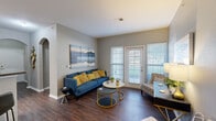 This single-story residence at 512 Stone Dr in Manhattan, Kansas, offers a thoughtfully designed layout across several well-defined living spaces. Dark hardwood-style flooring runs throughout, creating a cohesive and polished aesthetic from room to room.

The living room serves as a welcoming central space, featuring neutral gray walls, a large window, and a sliding glass door that floods the room with natural light while providing access to the outdoors. An arched entryway adds an architectural detail that distinguishes the space.

The dining area is positioned adjacent to the living room and features a pendant light fixture overhead, creating an intimate setting well-suited for everyday meals or entertaining.

The kitchen is equipped with warm-toned wood cabinetry, dark granite-style countertops, and standard appliances including an electric range and full-size refrigerator, offering practical functionality.

Two bedrooms provide comfortable retreats, each with windows that allow in natural light. The primary bedroom is notably spacious, while the secondary bedroom offers a cozy, well-proportioned layout.

The bathroom includes wood vanity cabinetry with granite-style counters and a tub-shower combination. A dedicated in-unit laundry room with full-size washer and dryer hookups and wire shelving adds everyday convenience.