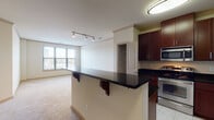 This single-floor residence offers a thoughtfully designed layout with distinct living areas connected by a functional floor plan. The kitchen serves as a central highlight, featuring rich dark-wood cabinetry extending to the ceiling, deep granite countertops, and a full suite of stainless steel appliances including a gas range, built-in microwave, refrigerator, and dishwasher. Light tile flooring runs throughout the kitchen, and a breakfast bar with decorative corbels provides a natural transition into the living area. Crown molding adds a refined detail throughout the space.

The living area is carpeted and benefits from natural light through large windows fitted with horizontal blinds, offering views of the surrounding urban landscape. Track lighting provides additional illumination. A built-in closet with shelving is accessible nearby.

The bedrooms are carpeted and feature crown molding, ceiling fans, and windows that bring in natural light. The primary bedroom includes access to a walk-in closet and an en-suite bathroom. Both bathrooms are finished with white tile surround tub-shower combinations and tile flooring, maintaining a clean, neutral aesthetic throughout.