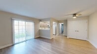This single-floor residence offers a thoughtfully designed layout with a blend of modern finishes and functional living spaces. The open living and dining area is highlighted by light hardwood-style flooring, neutral-toned walls, and a ceiling fan overhead. A large sliding glass door fills the space with natural light and provides direct outdoor access. A pass-through kitchen connects seamlessly to the living area and features contemporary wood-grain cabinetry, white quartz-style countertops, recessed lighting, and a full suite of white appliances including a refrigerator, range, microwave, and dishwasher. Light hardwood-style flooring continues throughout the kitchen, adding a cohesive feel. The bedrooms are carpeted and generously sized, each offering ample wall space, natural light from windows, and access to closet storage. Two bathrooms serve the unit: one features a sleek tub-and-shower combination enclosed by a frameless sliding glass door, paired with a white vanity; the second is a compact yet well-appointed half-style bath with a modern vanity, mirror, and wall-mounted cabinet. Throughout the unit, clean white trim, neutral paint tones, and updated fixtures create a bright, move-in-ready atmosphere.