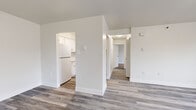 Located at 6 Bleecker Terr in Albany, NY, this 2-bedroom unit offers a clean, modern aesthetic across a thoughtfully arranged single-floor layout. The living area is bright and open, featuring light hardwood-style flooring and a large window that frames views of surrounding trees, creating an airy, welcoming atmosphere. The kitchen is efficiently designed with crisp white cabinetry, white appliances including a refrigerator and electric range, a single-basin sink, and matching hardwood-style flooring that extends from the main living areas. A central hallway connects the living spaces to the bedrooms, both of which are carpeted and feature windows with natural views. The primary bedroom is generously sized and includes access to a closet and an adjacent bathroom. The second bedroom is comfortably scaled and equally bright. A dedicated closet space with built-in shelving and a laundry hookup adds practical utility to the unit. Throughout, the space is finished with clean white walls, modern black-framed windows, and baseboard heating, contributing to a fresh, move-in-ready feel that balances functionality with understated style.