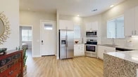 This well-appointed single-floor home combines modern finishes with a warm, welcoming atmosphere throughout. The kitchen serves as a functional centerpiece, showcasing white shaker cabinetry, granite countertops, a classic subway tile backsplash, and a full suite of stainless steel appliances including a French door refrigerator, range with over-the-range microwave, and dishwasher. Pendant lighting and an island with seating add both style and practicality. Light wood-look flooring flows seamlessly throughout the home, enhancing the sense of continuity and openness. The living room is bright and airy, filled with natural light from multiple windows and a sliding glass door that opens directly to a private outdoor patio—ideal for indoor-outdoor living. The bedrooms offer comfortable retreats, each with neutral tones, natural light, and closet storage. The primary bedroom connects to a well-designed en-suite bathroom featuring a double-sink vanity with granite countertops, white cabinetry, and a glass-enclosed tiled shower. A secondary bedroom includes a spacious reach-in closet. Recessed lighting, clean white trim, and a neutral color palette throughout give the home a fresh, modern feel that is both functional and inviting.