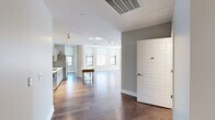 Located in the heart of downtown Rochester, NY, this thoughtfully designed three-bedroom, three-bathroom unit on East Main Street offers a refined urban living experience across a single, well-appointed floor. The open-concept kitchen and living area serves as the central hub of the home, featuring hardwood flooring, track lighting, and a sleek, modern kitchen outfitted with stainless steel appliances, a gas range, subway tile backsplash, and contemporary cabinetry with ample storage. Natural light flows generously throughout, with multiple windows framing views of the Rochester cityscape. The spacious primary bedroom is carpeted for comfort and includes its own en-suite bathroom with a modern floating vanity, white quartz countertop, and large framed mirror. The additional bedrooms are well-proportioned, with hardwood or carpeted floors and windows offering urban views. The bathrooms maintain a clean, minimalist aesthetic with neutral tile and quality fixtures. A dedicated in-unit laundry room houses a full-sized washer and dryer. Two closets provide practical storage solutions, complemented by wire shelving systems. The hallway connects all spaces cohesively, and the overall design palette of warm neutrals and modern finishes gives the unit a polished, contemporary feel throughout.