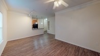 Located at 4070 Washington Rd in Augusta, Georgia, this single-floor unit offers a thoughtfully designed layout that balances comfort and functionality. The open-concept living and dining area is a standout feature, finished with warm hardwood-style flooring and accented by crown molding along the ceiling. Track lighting and a ceiling fan provide versatile illumination, while a window allows natural light to brighten the space. Built-in shelving adds a practical architectural touch to the living area.

The kitchen connects seamlessly to the main living space via a raised breakfast bar with dark granite-style countertops. Warm wood cabinetry, black appliances including an electric range and microwave, and a sink with pendant lighting overhead complete the kitchen. A dedicated utility area adjacent to the kitchen houses the washer and dryer connections alongside the electrical panel.

The bedroom features plush carpeting, a ceiling fan with light fixture, and a window dressed with blinds that filters natural light into the room. The bathroom is finished with wood-look flooring and includes a warm wood vanity with a countertop sink, a large mirror, and a separate toilet area, offering a clean and functional design throughout the space.