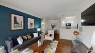 This single-story residence at Madison Place Circle in Kernersville, NC, offers a well-designed open-concept layout that connects the living, dining, and kitchen areas into one cohesive space. The living room is a standout, anchored by a bold teal accent wall adorned with framed artwork, crown molding, and a textured ceiling. Hardwood-style flooring flows throughout, adding warmth and continuity. Large windows and a sliding glass door flood the space with natural light, while a sunlit bonus nook adjacent to the living area provides an ideal spot for a home office or reading area.

The kitchen features white cabinetry, a peninsula with a light stone-look countertop, black appliances including a refrigerator, range, and microwave, plus pendant lighting overhead. A dining area sits conveniently nearby.

Two bedrooms each feature distinctive accent walls—one in deep charcoal, the other in vibrant orange—along with ample closet space and windows that invite natural light. Both full bathrooms are finished with white tile tub-shower combinations, light countertops, white cabinetry, and bright vanity lighting, offering a clean and functional aesthetic throughout.