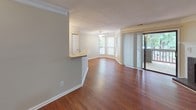 This single-floor, 2-bedroom, 2-bathroom residence offers a thoughtfully designed layout with warm hardwood-style flooring throughout. The spacious living room serves as the centerpiece of the home, highlighted by a classic fireplace with a white-painted mantle, elegant crown molding, and neutral-toned walls that create an inviting atmosphere. Large windows and a sliding glass door flood the space with natural light while providing views of the greenery outside.

The kitchen is well-equipped with medium-toned wood cabinetry, a full suite of black appliances including a refrigerator, range, and over-the-range microwave, and a convenient breakfast bar peninsula with a sink — ideal for casual dining and meal prep. Track lighting illuminates the workspace effectively.

Both bedrooms are generously sized, featuring the same warm hardwood-style flooring and neutral walls, with windows that bring in natural light. Each room offers ample space for furnishings and personal use.

The two bathrooms are clean and functional. One features a rich wood-toned vanity with a wide mirror and light countertop, while the second includes a full tub-shower combination with white tile surround. Together, they provide practical comfort and convenience throughout this well-maintained home.