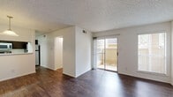 This single-floor residence offers a well-organized layout with distinct living, sleeping, and functional zones. The main living area is finished with dark hardwood-style flooring that extends throughout, complemented by clean white walls and a textured ceiling. A sliding glass door opens directly to a private balcony, allowing natural light to fill the space and offering outdoor views of a wood-railed patio. A pendant light fixture highlights a defined dining area adjacent to the living space.

The galley-style kitchen features dark cabinetry paired with light countertops, a double stainless steel sink, and stainless steel appliances including an electric range and over-the-range microwave. Wood-look flooring continues through the kitchen, maintaining visual consistency.

The bedroom is carpeted in a neutral tone and includes a full-width mirrored sliding closet, adding depth and storage. A ceiling light fixture provides overhead illumination. The bathroom includes a white vanity with storage, a full tub-shower combination with white tile surround, and dark hardwood-style flooring that ties back to the main living areas. The overall ambiance is clean, neutral, and move-in ready.