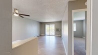 Located at 1800 Nueva Vista Dr in Denver, Colorado, this one-bedroom, one-bathroom unit offers a practical and well-appointed single-floor layout. The living room is bright and open, featuring light wood-style flooring, a textured ceiling, a ceiling fan, and a wall-mounted HVAC unit. Sliding glass doors lead to a private balcony, filling the space with natural light. Baseboard heating runs throughout, providing consistent comfort year-round. The kitchen is thoughtfully updated with crisp white cabinetry, marble-look countertops, a stainless steel sink, and a full suite of black appliances including a refrigerator, electric range, over-the-range microwave, and dishwasher. A skylight adds brightness to the cooking area. The bedroom is carpeted and comfortably sized, offering a closet with sliding doors, a window with natural light, and baseboard heating. The bathroom includes a full tub-shower combination with clean white surrounds and modern fixtures. Neutral gray tones are carried throughout the unit, creating a cohesive and understated aesthetic that is move-in ready.