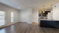 This well-appointed 2-bedroom, 2-bathroom single-floor residence at 11300 Expo Blvd in San Antonio, TX offers a thoughtfully designed layout with a cohesive, neutral color palette throughout. The living area features rich hardwood-style flooring and elegant crown molding, creating a polished ambiance that extends into the adjoining dining room. The dining space is framed by a pass-through window that connects directly to the kitchen, allowing for easy interaction and natural flow between rooms. The kitchen is finished with white cabinetry and tile flooring, offering a clean and functional workspace complemented by a dedicated pantry for added storage. Both bedrooms are generously proportioned, with the primary bedroom benefiting from multiple windows that invite natural light and views of the surrounding greenery. Each bedroom is served by its own walk-in closet with built-in shelving and hanging rods, providing ample storage. The bathrooms feature tub-shower combinations with tiled surrounds, wood-style flooring, and white vanity cabinetry. Additional highlights include multiple hallways for efficient circulation, a private patio for outdoor enjoyment, and three total closets throughout the unit, ensuring practical storage solutions across the entire residence.