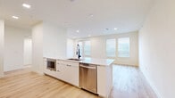 This thoughtfully designed one-bedroom, one-bathroom residence in Round Rock, Texas offers a clean, modern aesthetic with a bright and airy open-concept layout. Light wood flooring flows seamlessly throughout the entire space, complementing the crisp white walls and recessed lighting that create a fresh, contemporary feel.

The kitchen is a standout feature, boasting a large central island with a white quartz countertop and an integrated sink with a matte black pull-down faucet. Flat-front white cabinetry, a marble-style tile backsplash, a stainless steel range hood, and a full suite of stainless steel appliances — including a refrigerator, dishwasher, and oven — complete this well-appointed cooking space. The kitchen opens directly to the living area, which is bathed in natural light from multiple windows fitted with blinds.

The bedroom is a comfortable, well-proportioned retreat with dual windows and a ceiling fan. It includes access to a spacious walk-in closet with wrap-around shelving and hanging rods. The bathroom features a sleek glass-enclosed walk-in shower with large-format marble-look tile, matte black fixtures, and white cabinetry for ample storage. The overall ambiance of the space is clean, minimalist, and move-in ready.