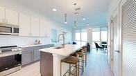 Located at 321 Main St in Hackensack, NJ, this well-appointed 1-bedroom, 2-bathroom residence offers a thoughtfully designed open-concept layout with contemporary finishes throughout. Light wood-look tile flooring flows seamlessly across the entire space, complementing the bright, neutral palette.

The combined kitchen and living area serves as the heart of the home. The kitchen features two-tone cabinetry — white upper cabinets paired with gray lower cabinets — white subway tile backsplash, stainless steel appliances, and a generous waterfall-edge island with seating for multiple guests, illuminated by elegant gold pendant lights. The living area is anchored by oversized windows with roller shades that frame expansive city views of Hackensack's skyline.

The spacious primary bedroom receives abundant natural light through large windows overlooking the cityscape and includes a walk-in closet with built-in shelving. Two full bathrooms serve the residence: one features a sleek glass-enclosed walk-in shower with white tile surround and a modern vanity, while the second offers a tub-shower combination with matching clean-lined finishes. Throughout, the design maintains a cohesive modern aesthetic defined by clean lines, natural light, and quality materials.