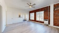 Located on S Manhattan Place in the heart of Los Angeles, this 1-bedroom, 1-bathroom unit offers a well-considered single-level layout across a comfortable footprint. The living room serves as the centerpiece of the space, showcasing a striking exposed brick accent wall, large multi-pane windows that flood the room with natural light, light-toned hardwood flooring, and a ceiling fan overhead. A charming arched doorway connects the living area to the hallway, adding a classic architectural detail to the otherwise clean, modern aesthetic. The bedroom continues the light hardwood flooring and features its own ceiling fan, a dedicated closet, and a large window framing views of the surrounding neighborhood with the exposed brick surround providing a warm, textural contrast. The kitchen is thoughtfully designed with white shaker cabinetry, a stainless steel full-size refrigerator, a gas range, and wood-look tile flooring that complements the overall palette. The bathroom is clean and functional, featuring a combined tub and shower, tile flooring, a vanity, and a frosted window for natural light and privacy. A hallway with closet storage connects the rooms efficiently. Throughout, the space balances classic Los Angeles character with updated, modern finishes.