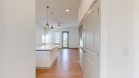 This thoughtfully laid-out 2-bedroom, 1-bathroom residence offers a clean, modern aesthetic across a single floor. The open-concept kitchen and living area serves as the heart of the home, featuring light wood-style flooring, white shaker cabinetry, quartz countertops, and a central kitchen island ideal for both meal prep and casual dining. Stainless steel appliances — including a refrigerator with ice maker, electric range, microwave, and dishwasher — complete the kitchen. Stylish pendant lighting hangs above the island, while a ceiling fan with light kit anchors the living area, which opens toward a glass door and windows that invite natural light and outdoor views. The two bedrooms offer a comfortable retreat; the primary bedroom features plush carpeting, multiple windows with exterior views, and ample wall space. The second bedroom is finished with the same light wood-style flooring seen throughout the main living areas and benefits from generous natural light. The full bathroom is finished with vertical white subway tile surrounding a soaking tub and shower combination, wood-style flooring, and a vanity with a quartz countertop. A dedicated closet provides additional storage, rounding out this efficiently designed and move-in-ready residence.