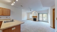 Located at 2707 Park Place Ln in Janesville, Wisconsin, this single-floor residence offers a well-designed, open layout that balances comfort and functionality. The spacious living and dining area serves as the heart of the home, highlighted by a tile-surround fireplace with a warm wood mantel, a ceiling fan, and track lighting overhead. Natural light flows in through multiple windows, and a set of sliding glass doors opens to a private outdoor balcony, extending the living space outdoors. The kitchen is thoughtfully designed with warm wood cabinetry, ample counter space, tile flooring, and a full suite of white appliances including a gas range, microwave, and refrigerator. A peninsula counter connects the kitchen to the living area, creating an open and sociable flow. The primary bedroom is generously sized, featuring plush carpeting, a ceiling fan, a walk-in closet, and windows that bring in natural light. The en-suite bathroom is equipped with a granite-topped vanity, a soaking tub, and tile flooring. Additional bedrooms offer carpeted floors and ceiling fans, providing comfortable, versatile spaces. Throughout the home, warm wood trim accents and neutral tones create a cohesive and inviting atmosphere.