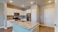 Located at 575 Concord Rd in Jefferson, GA, this well-appointed single-story residence offers a thoughtfully designed open-concept floor plan ideal for comfortable everyday living. The kitchen serves as the centerpiece of the main living area, showcasing a large granite-topped island with an undermount sink, white shaker-style cabinetry, granite countertops, and a full suite of stainless steel appliances including a refrigerator, range, microwave, and dishwasher. Recessed lighting illuminates the kitchen and living area, which flows seamlessly together across durable hardwood-style flooring. The living room benefits from multiple windows fitted with blinds, allowing for ample natural light and outdoor views. The bedroom is a well-proportioned, tranquil retreat featuring a ceiling fan, a large window, and the same hardwood-style flooring. A spacious walk-in closet with multi-tier wire shelving provides generous storage. The bathroom is clean and functional, featuring a granite-topped vanity with white cabinetry, a full tub-shower combination with tiled surround, and hardwood-style flooring. Neutral wall tones and consistent finishes throughout the residence create a cohesive and modern aesthetic.