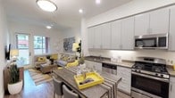 This thoughtfully designed single-floor residence offers a seamless blend of modern aesthetics and functional living. The open-concept layout connects the kitchen and living area, creating a bright, airy atmosphere illuminated by recessed lighting and natural light from large windows. The kitchen is outfitted with sleek grey cabinetry, dark countertops, a full suite of stainless steel appliances including a gas range, microwave, dishwasher, and French door refrigerator, plus a central island with seating — ideal for casual dining and entertaining. The living area flows naturally from the kitchen, featuring wood-style flooring and a sliding door that opens to an outdoor area. The bedroom is a comfortable retreat with plush carpeting, ample natural light from multiple windows, and a ceiling fan. A walk-in closet provides generous storage. The full bathroom includes a tub-shower combination, vanity with dark countertop, and wood-style flooring. A dedicated in-unit laundry closet with a stacked washer and dryer adds everyday convenience. A flexible secondary space, suitable as a home office or den, completes the layout. The consistent use of neutral tones with modern fixtures creates a cohesive, contemporary feel throughout.