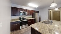 Located at 211 Kelly Rd in Clemson, SC, this single-story home offers four bedrooms, three full bathrooms, and a well-designed layout that maximizes functionality. The kitchen is a standout feature, showcasing rich dark cabinetry, granite countertops, stainless steel appliances including a refrigerator, range, and microwave, and a central island with a sink and pendant lighting — all open to the living area via a wide doorway. Hardwood-style flooring runs through the main living and kitchen areas, providing a clean and cohesive look. The bedrooms are carpeted for comfort, with several rooms featuring ceiling fans and natural light from windows with outdoor views. The primary bedroom includes walk-in closet access and is served by a private bathroom with a vanity and tub-shower combination. Additional bathrooms are similarly appointed with dark wood vanities and tub-shower units. The dedicated laundry room houses a full-size washer and dryer with overhead shelving for added storage. Three closets throughout the home provide ample organization options. With two hallways connecting the rooms efficiently, the layout ensures a practical and comfortable flow throughout this Clemson residence.