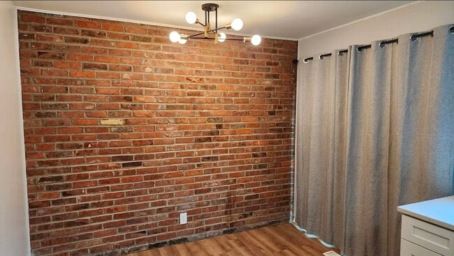 A stylish dining area showcases an exposed brick accent wall, modern sputnik chandelier, and warm wo - 21 Richmond Sq