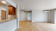 Located at 1630 Fordem Ave in Madison, Wisconsin, this single-floor residence offers a well-designed layout with a clean, neutral aesthetic throughout. The open living area is finished with light wood-tone laminate flooring and features large sliding glass doors with vertical blinds that allow generous natural light and outdoor views. A wall-mounted air conditioning unit and baseboard heating provide year-round climate control. The kitchen is positioned adjacent to the living space in a semi-open layout, featuring rich dark wood cabinetry, granite-style countertops, a stainless steel sink, and a dishwasher. A dedicated utility area off the kitchen houses a stacked washer unit and refrigerator, adding practical convenience. The bedrooms are carpeted for comfort and include windows with blinds that bring in natural light, along with baseboard heating. The unit includes two bathrooms, each featuring warm wood vanities, white countertops, tiled shower-tub combinations, and brushed nickel fixtures and grab bars. A ceiling fan is installed in the main living or dining area, enhancing airflow. The overall interior is finished in soft gray tones with clean white trim, creating a bright, cohesive, and move-in-ready living environment.