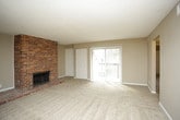 This single-story home presents a well-organized layout with a comfortable, neutral aesthetic throughout. The living room serves as a central gathering space, highlighted by a full-height brick fireplace that functions as a striking focal point. The room features plush carpeting and connects openly to adjacent areas, with a ceiling fan adding practical comfort.

The kitchen is equipped with warm-toned wood cabinetry extending to the upper walls, granite-look countertops offering generous prep space, and black appliances including an electric range and dishwasher. A stainless steel sink completes the functional workspace, all set atop wood-look flooring with a textured ceiling above.

The bedrooms are carpeted and finished in neutral tones, each offering a sliding-door closet with built-in rods for storage. Windows allow natural light to filter into each room, contributing to a bright and airy feel.

Two full bathrooms serve the home, both consistent in their finishes. Each features rich wood-toned vanity cabinetry, granite-look countertops, and wood-look plank flooring. One bathroom includes a walk-in shower with chrome fixtures, while the other offers a full tub-shower combination. Together, the spaces reflect a cohesive and practical design throughout the home.