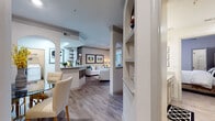This thoughtfully designed single-floor residence offers a seamless blend of comfort and style across its generously proportioned layout. The open-concept living area serves as the heart of the home, featuring warm wood-look flooring, crown molding, and elegant arched architectural details that frame a dedicated study nook bathed in natural light from large windows. The living room is anchored by neutral tones accented with teal and gold, creating a refined yet welcoming ambiance.

The galley-style kitchen is outfitted with granite countertops, gray shaker cabinetry, stainless steel appliances, and light wood-look flooring, offering both function and style. Adjacent to the kitchen, a defined dining area accommodates intimate gatherings beneath a statement chandelier.

The bedrooms are carpeted for comfort, each featuring ceiling fans and ample natural light. One bedroom showcases a bold upholstered headboard with stylish monochromatic décor, while another offers a serene retreat with direct access to a full bathroom. The bathroom includes granite vanity countertops, gray cabinetry, and a soaking tub. A spacious walk-in closet with wire shelving and built-in organizational systems provides exceptional storage. Built-in shelving units in the main living corridor add both display space and architectural character throughout.