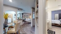 This thoughtfully designed single-floor residence offers a seamless blend of comfort and style across its generously proportioned layout. The open-concept living area serves as the heart of the home, featuring warm wood-look flooring, crown molding, and elegant arched architectural details that frame a dedicated study nook bathed in natural light from large windows. The living room is anchored by neutral tones accented with teal and gold, creating a refined yet welcoming ambiance.

The galley-style kitchen is outfitted with granite countertops, gray shaker cabinetry, stainless steel appliances, and light wood-look flooring, offering both function and style. Adjacent to the kitchen, a defined dining area accommodates intimate gatherings beneath a statement chandelier.

The bedrooms are carpeted for comfort, each featuring ceiling fans and ample natural light. One bedroom showcases a bold upholstered headboard with stylish monochromatic décor, while another offers a serene retreat with direct access to a full bathroom. The bathroom includes granite vanity countertops, gray cabinetry, and a soaking tub. A spacious walk-in closet with wire shelving and built-in organizational systems provides exceptional storage. Built-in shelving units in the main living corridor add both display space and architectural character throughout.