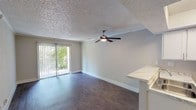 Located at 614 S 1st St in Austin, TX, this single-floor unit sits in one of the city's most sought-after neighborhoods, offering convenient access to South Congress, local dining, and entertainment. The open living area is finished with rich wood-look flooring and a textured ceiling, complemented by a ceiling fan that promotes comfortable airflow year-round. A sliding glass door fills the space with natural light and opens to a private balcony overlooking lush greenery, creating a pleasant indoor-outdoor connection. The kitchen is thoughtfully appointed with crisp white cabinetry, marble-style countertops, a double-basin stainless steel sink, and black appliances including an electric range and full-size refrigerator. A peninsula counter with a breakfast bar separates the kitchen from the living area, enhancing the open feel. The hallway connects the main living spaces to a well-sized bedroom featuring its own ceiling fan, wood-look flooring, and a window allowing natural light. The bathroom includes a white vanity with a marble-style countertop, chrome fixtures, and a lighted mirror. Additional storage is accessible via a walk-in closet visible from the bathroom. Throughout the unit, neutral tones and clean finishes create a bright, cohesive aesthetic well-suited for Austin living.