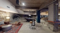 Located at 900 Third Ave N in downtown Nashville, this single-floor venue delivers a bold industrial-chic aesthetic that blends raw architectural elements with curated, stylish interiors. Polished concrete floors stretch throughout the open layout, complemented by exposed concrete ceilings with visible ductwork and structural columns that underscore the space's urban character.

A commanding large-scale mural of a pair of eyes dominates one wall, serving as an immediate focal point and lending the space a distinct artistic identity. Adjacent to the mural, a full-size billiards table sits beneath a crystal chandelier, creating an unexpected juxtaposition of textures and styles.

The bar area is a standout feature, complete with a live-edge wood-topped island, leather bar stools, pendant lighting, and a deep navy accent wall displaying mounted whiskey barrels — a nod to Nashville's distilling heritage. Nearby, a lounge nook is anchored by exposed stone and brick walls, offering a warm, intimate contrast to the broader open areas. Leather sectional seating, layered Persian-style rugs, and mid-century modern chairs create comfortable gathering spots throughout.

A dining area with round wooden tables and upholstered chairs is separated by sheer drapery panels, providing a more defined setting within the open floor plan. Dramatic arched entry doors and teal accent walls throughout add color and character, making this venue a versatile and visually engaging destination.