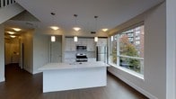 Located at 111 Morgan St in Stamford, Connecticut, this modern two-floor residence offers a thoughtfully designed living experience with clean lines and contemporary finishes throughout. The open-concept kitchen serves as a central highlight, anchored by a large white waterfall island with an integrated sink, ideal for both meal preparation and casual dining. White shaker-style cabinetry lines the walls, complemented by stainless steel appliances including a gas range, microwave, and refrigerator. Pendant lighting hangs above the island, adding a refined touch to the space. Durable wood-style flooring runs throughout, providing warmth and continuity across the layout. A defining feature of the main living area is the expansive floor-to-ceiling windows that flood the space with natural light and frame lush, tree-lined views of the surrounding Stamford streetscape. The two-floor layout provides clear separation between living and private areas, enhancing both functionality and privacy. The overall ambiance is bright, airy, and modern, making it well-suited for those seeking a polished urban living environment in the heart of Stamford.